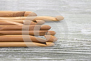 Wooden natural bamboo crochet hooks on the table. Various sizes. Creative work place for homemade crafts. Top view.