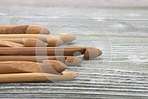 Wooden natural bamboo crochet hooks on the table. Various sizes. Creative work place for homemade crafts. Top view.