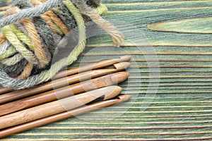 Wooden natural bamboo crochet hooks and yarn ball on the green table. Creative work place for homemade crafts. Top view, place for