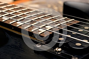 Wooden neck of a black guitar close up