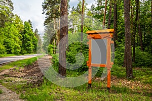 The wooden notice board near the road.