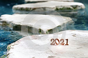 Wooden number 2021 on rock marble on pool background