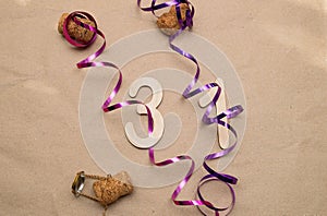 Light wooden numbers 31 lie on craft paper with champagne corks, packing tape and muzlet
