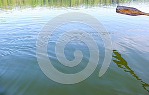 Wooden oar, water drops and ripples