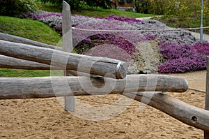 Wooden obstacle course for children made of solid poles and logs. clade is finished at end with a metal ring preventing the edges