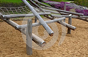 Wooden obstacle course for children made of solid poles and logs. clade is finished at end with a metal ring preventing the edges