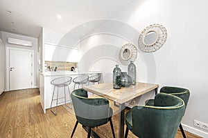 Wooden office table in an island kitchen with white marble top and gray veins and green velvet chairs