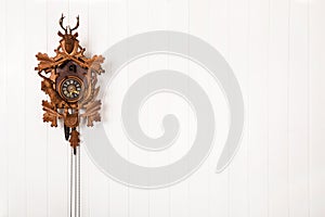 Wooden old cuckoo clock hanging on a white wall.