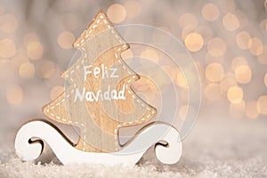 Wooden ornament cutout in the shape of a pine tree - translation text Feliz Navidad - merry christmas