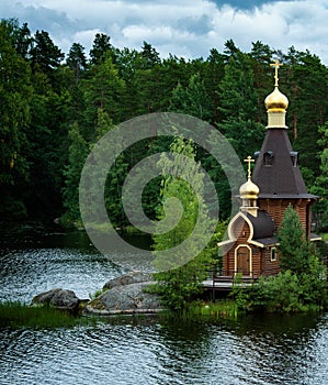 Wooden ortodox church of the Apostle Saint Andrew near the forest lake in Russia
