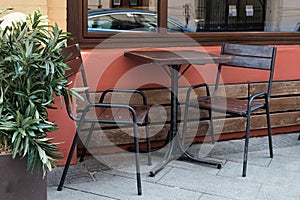Wooden outdoor furniture - table and two chairs with metal legs at the entrance to the cafe