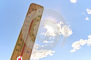 Wooden outdoor thermometer background scorching summer sun and blue sky.