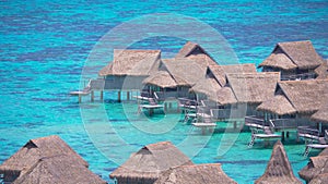 Wooden overwater villas of luxury holiday resort rest in the emerald ocean.