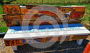 Wooden painted peace bench created by children with translations of peace in different languages