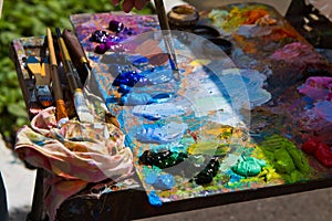 Wooden palette, mess of fresh bright colorful oil paints mixed in disorder, outdoor painting plein air, inspiration postcard