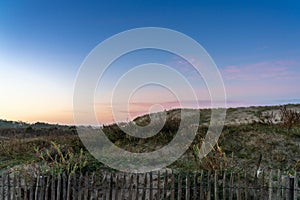 Wooden palisade fence and beach and sand dunes at sunrise