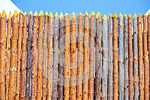 A wooden palisade made of logs sharpened on a sharp
