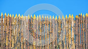 A wooden palisade made of logs sharpened on a sharp