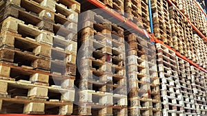 Wooden pallets for product distribution and transportation are stacked in rack of warehouse