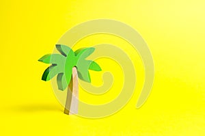 Wooden palm tree on an yellow background. Conceptual leisure and vacation, entertainment and relaxation. Tours and cruises