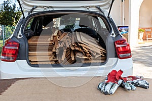 Wooden panels loaded into rear of white car with red workmans gloves in the foregorund photo