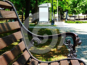 Wooden park bench detail with bus shelter in a distance