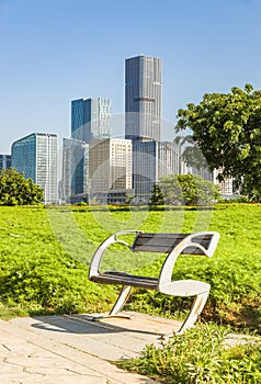 Wooden park bench at sunrise in a park with a cityscape background