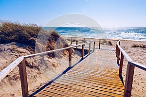 Wooden path at Costa Nova d'Aveiro, Portugal, over sand dunes with ocean view, summer evening. Wooden footbridge of Costa Nova