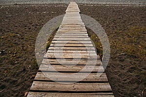 Wooden path on the sandy beach. Beach boardwalk with sand texture background