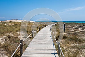 The wooden path to the torquoise water with white sand beach in a sunny day