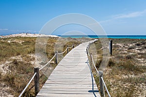 The wooden path to the torquoise water with white sand beach in a sunny day photo