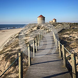 Wooden path to the windmills on the ocean beach against clear sky near Esposende, Portugal, December 2017