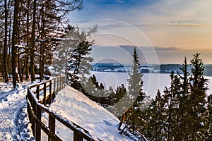 The Wooden Path Under the Snow with a View of Frozen Lake