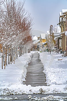 Wooden pathway amid trees and homes in Daybreak Utah viewed in winter