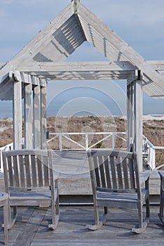 Wooden Patio and two rocker chairs overlook ocean.