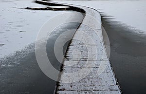 wooden pedestrian bridge over frozen snowy river pond lake no railing