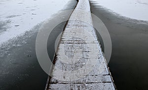 wooden pedestrian bridge over frozen snowy river pond lake no railing