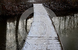 wooden pedestrian bridge over frozen snowy river pond lake no railing