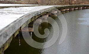 wooden pedestrian bridge over frozen snowy river pond lake no railing