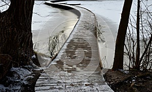 wooden pedestrian bridge over frozen snowy river pond lake no railing