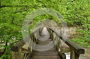 Wooden pedestrian bridge over river. Springtime