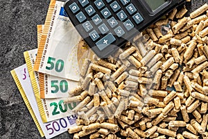 Wooden pellets, euro banknotes and calculator. Ecologic heating