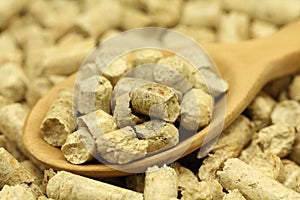 Wooden pellets in a measuring spoon background