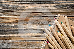 Wooden pencils and recycled notebook on a wooden background, flat lay.