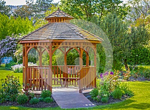 Wooden pergola at the beautiful green garden with flowers. Beautiful gazebo