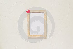 Wooden photo frame with red heart on white wall baxkground. Minimal flat lay with copy space