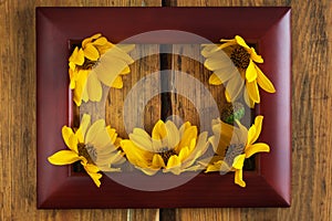 Wooden photo frame with yellow flowers on a brown wood background. Hello autumn concept