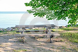 A wooden picnic table sits on the beach next to the water.