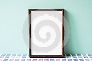 Wooden picture frame on blue tile shelf. mint wall background. copy space