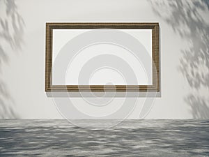 Wooden picture frame hang on the wall with Trees shadow on the wall.